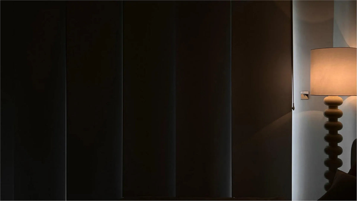 A dark bedroom with blackout shades and dim lighting.