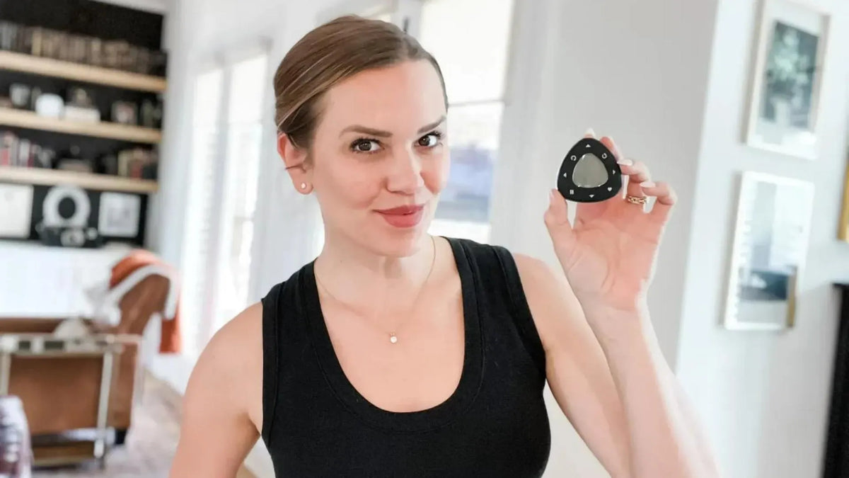 Woman holding a smart remote for window treatments in a stylish living room