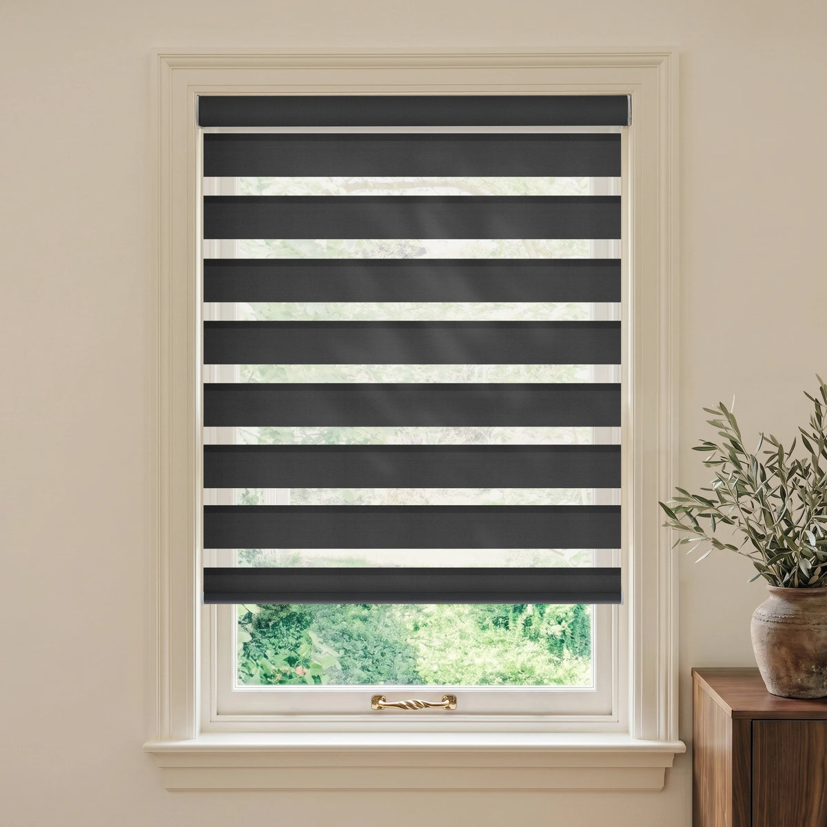 Luxury Black motorized room-darkening zebra blind in a beige room beside a wooden table and olive branches.