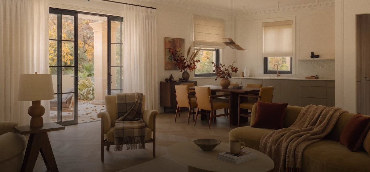 Open-plan living, dining, and kitchen space with ivory curtains, a beige Roman shade, and a matching roller shade.