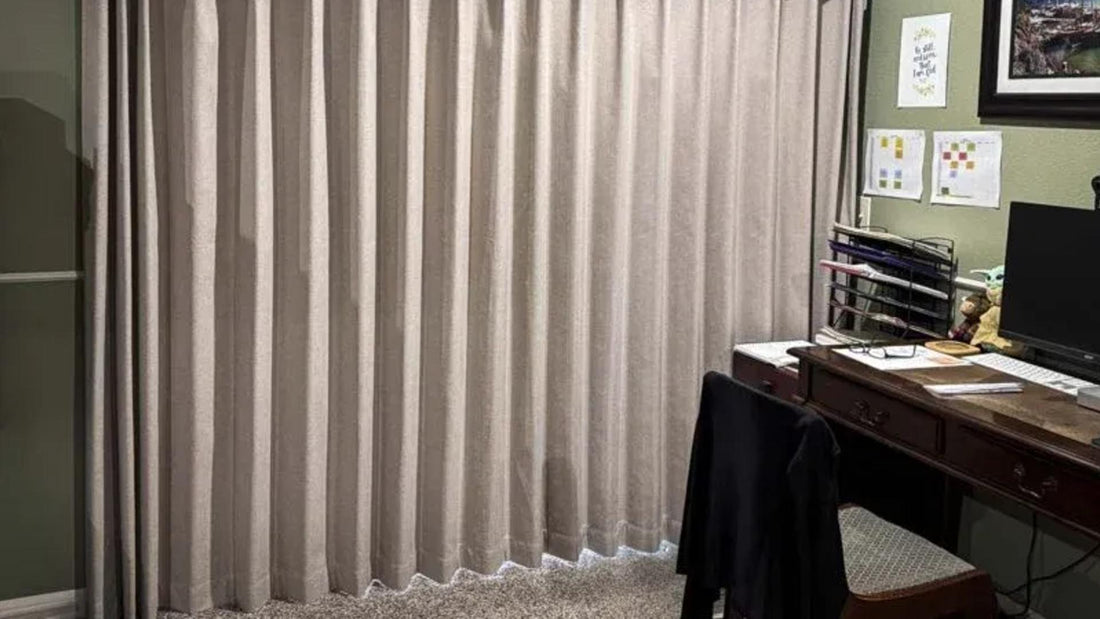 Beige vertical blinds in a home office with desk, computer, and paperwork visible.