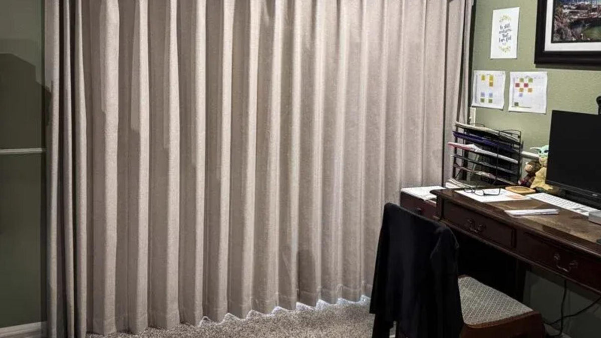 Beige vertical blinds in a home office with desk, computer, and paperwork visible.