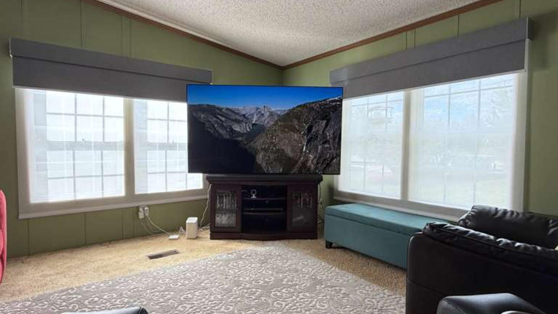 Living room with large windows, graywind valances, light-filtering roller shades, and a TV on a cabinet.