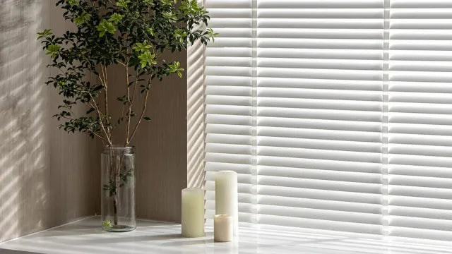 Living room with sunlit windows and furniture, promoting sun blocking window shades.