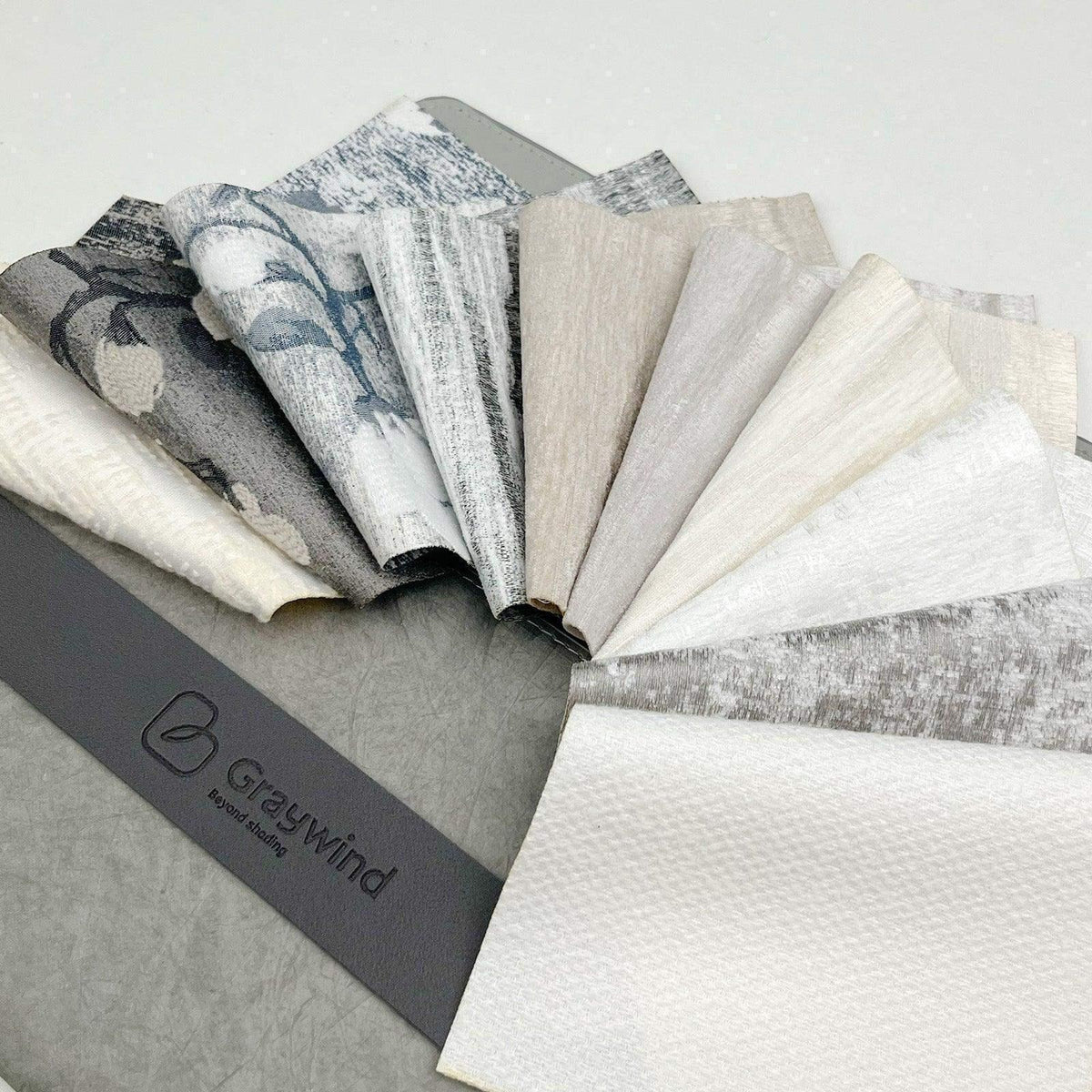 Assorted neutral fabric swatches for custom window treatments on a sample display ring.