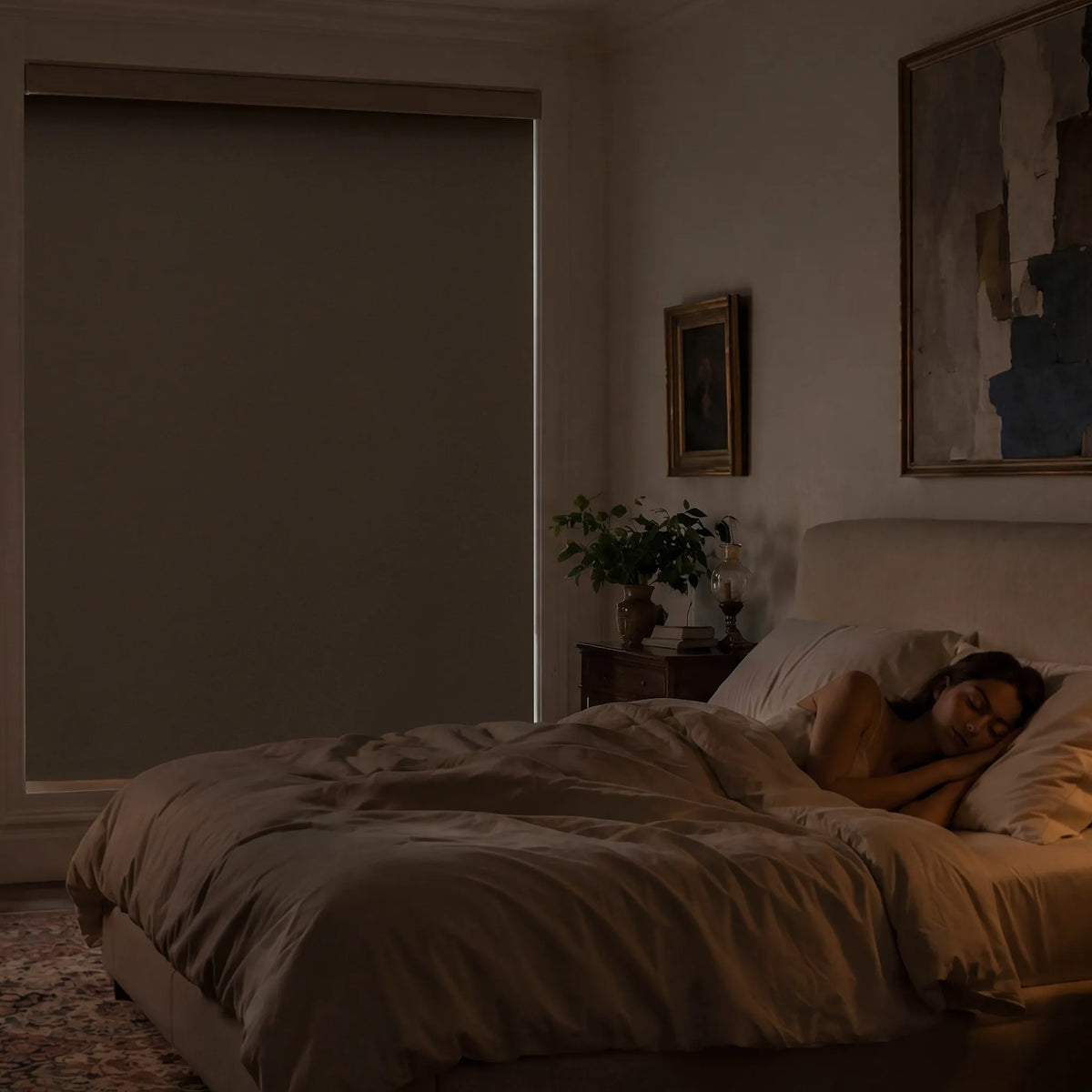 Person lying in bed in a dimly lit bedroom with a painting on the wall.