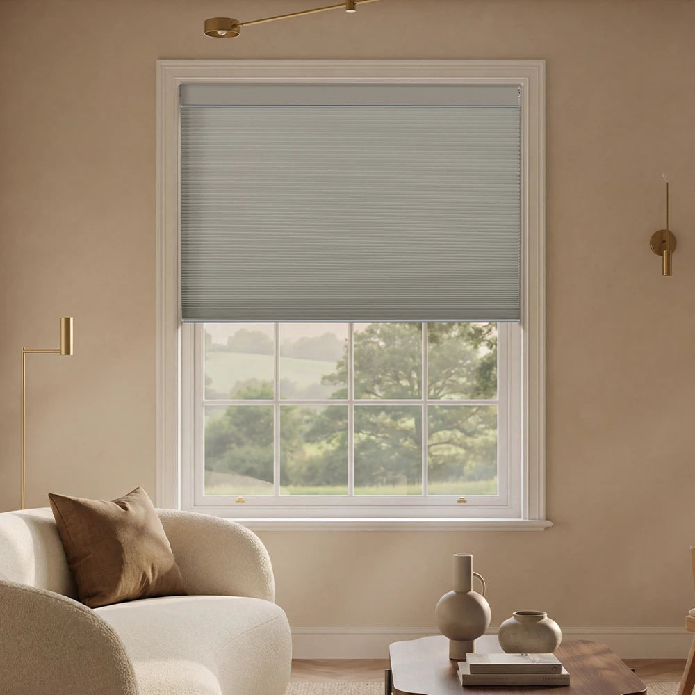 Living room with a window featuring a cordless top down bottom up cellular shade, beige sofa, and decorative items.