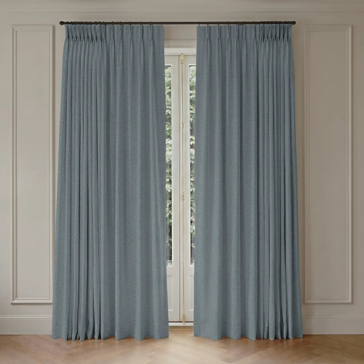 Pair of blackout curtains with rod hanging in front of a window with light-colored walls.