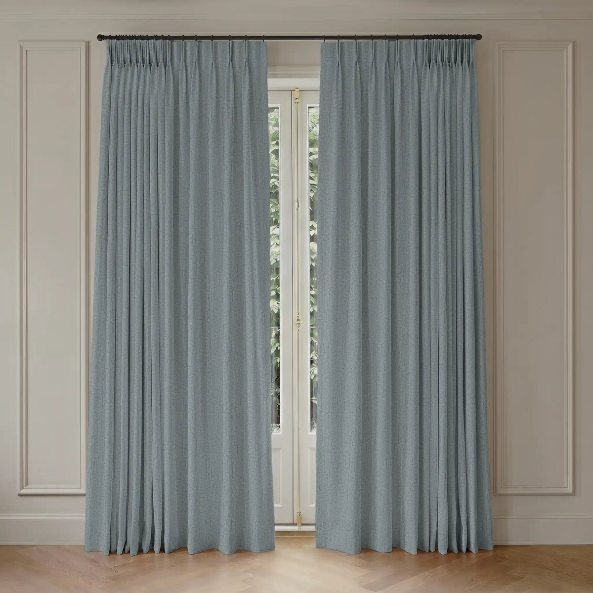 Pair of blue blackout curtains hanging in front of a window with light-colored walls.