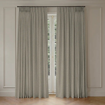 Pair of blackout curtains hanging in front of a window with light-colored paneled walls.