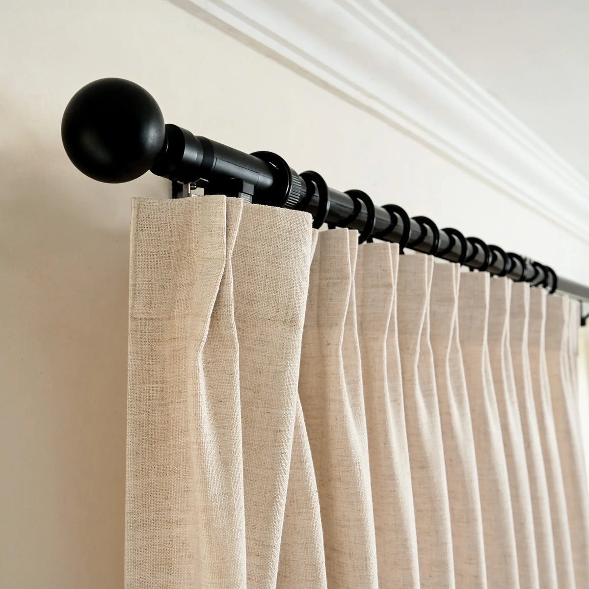 Curtain rod with beige curtains against a white wall