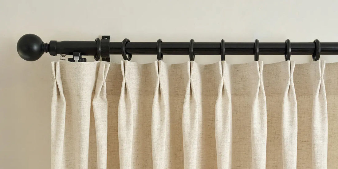 Beige curtains with a black curtain rod on a beige wall