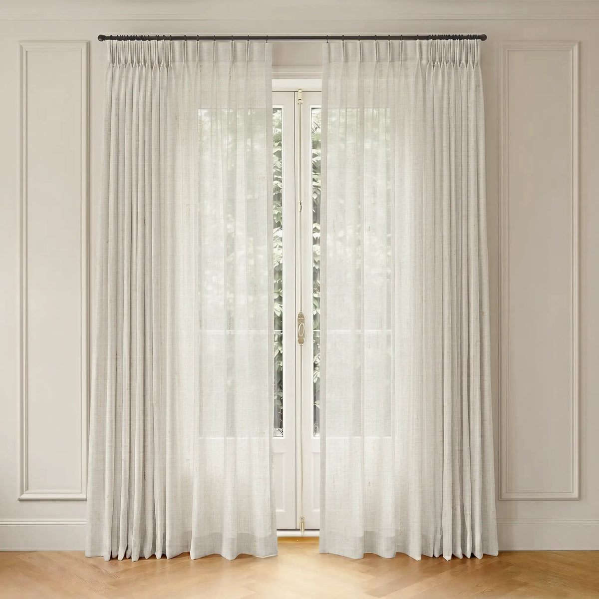 White curtain with rod hanging in front of a window with a neutral wall background.