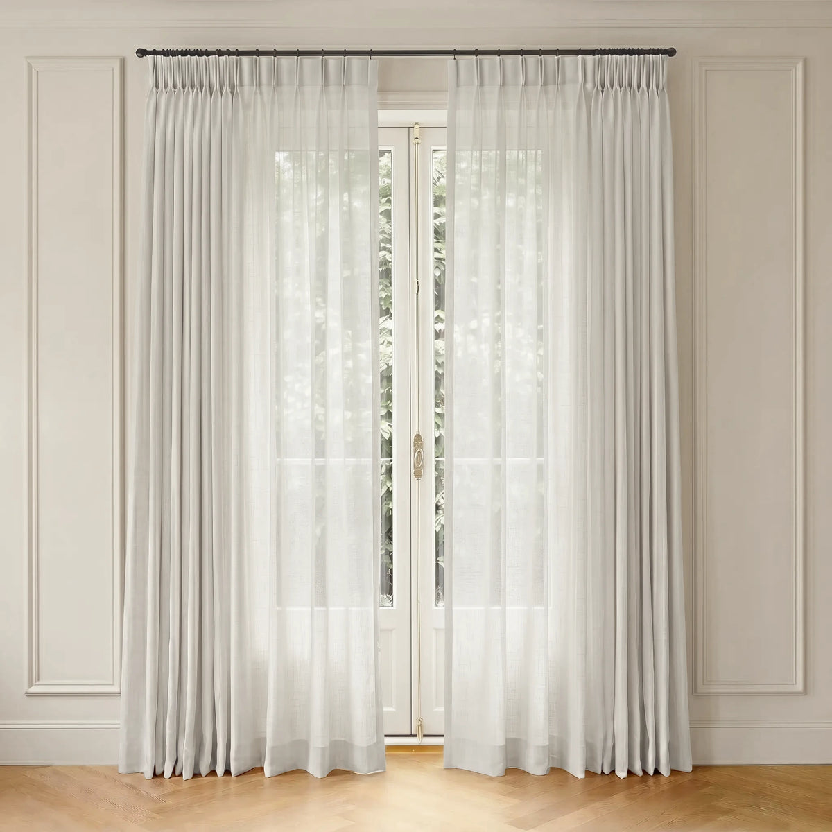 Sheer white curtain with rod hanging in front of a window with a neutral wall background
