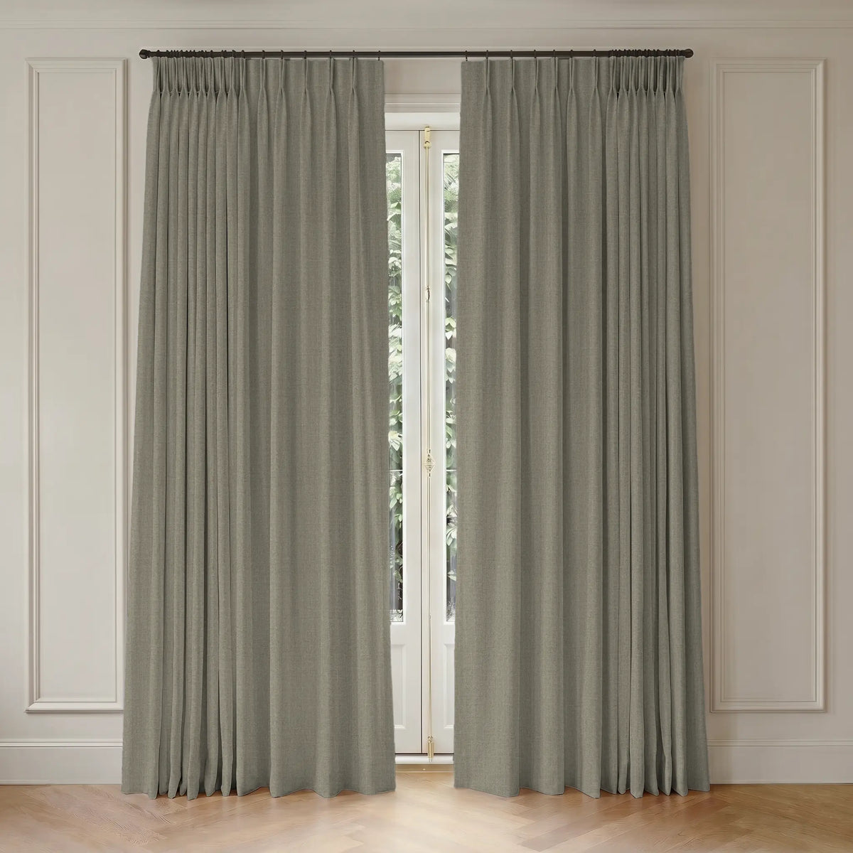 Pair of beige room darkening curtains hanging in front of a window with white trim.