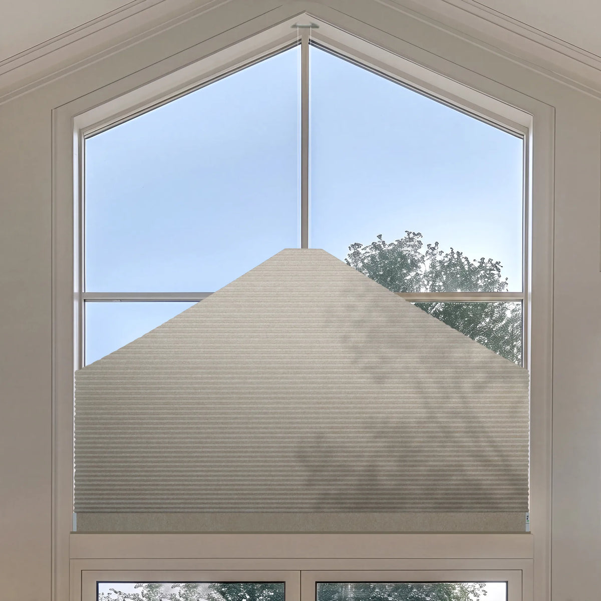 A large white Elongated Triangle Cellular Shades installed on a tall, multi-pane arched window, shown with natural light and outdoor sky visible.
