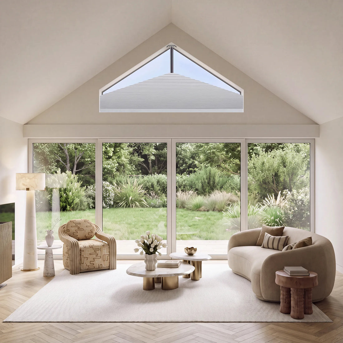 A modern living room with a curved beige sofa, patterned armchair, wooden coffee tables, and a large white sElongated Triangle Cellular Shades installed in a gabled roof, overlooking a green garden.