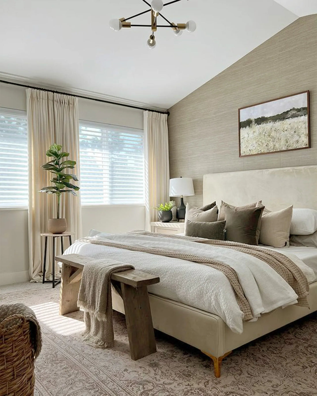 An elegant bedroom with a textured feature wall and windows dressed in Shangri-La shades and creamy floor-length curtains.