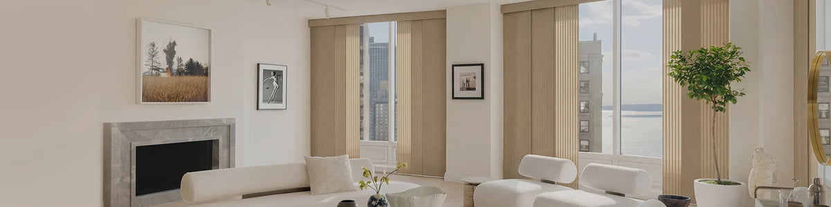 A modern living room with beige panel track blind installed on tall windows, alongside a fireplace, white sofas, and a potted plant.