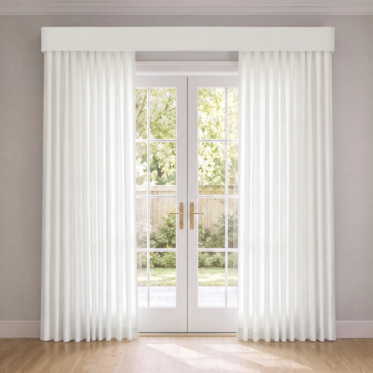 A pair of long white sheer curtains hanging on a window with white double glass doors, set in a bright room with light gray walls and a wooden floor.