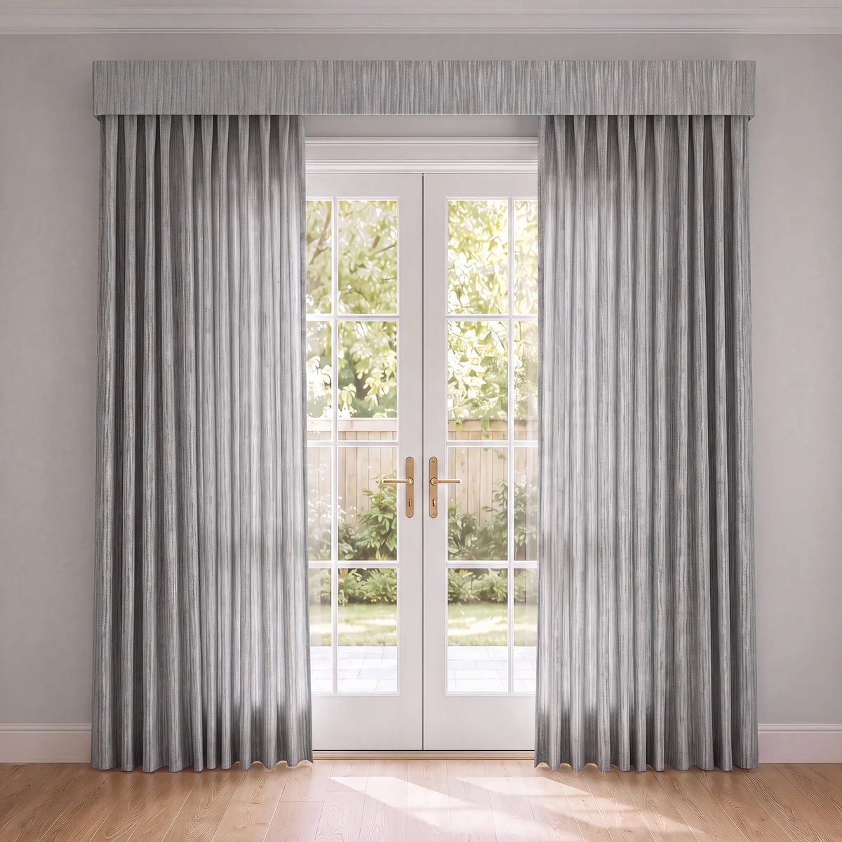 A pair of light gray pleated curtain panels with a matching pleated valance hanging on either side of white French doors in a bright room with light gray walls and a wood floor.