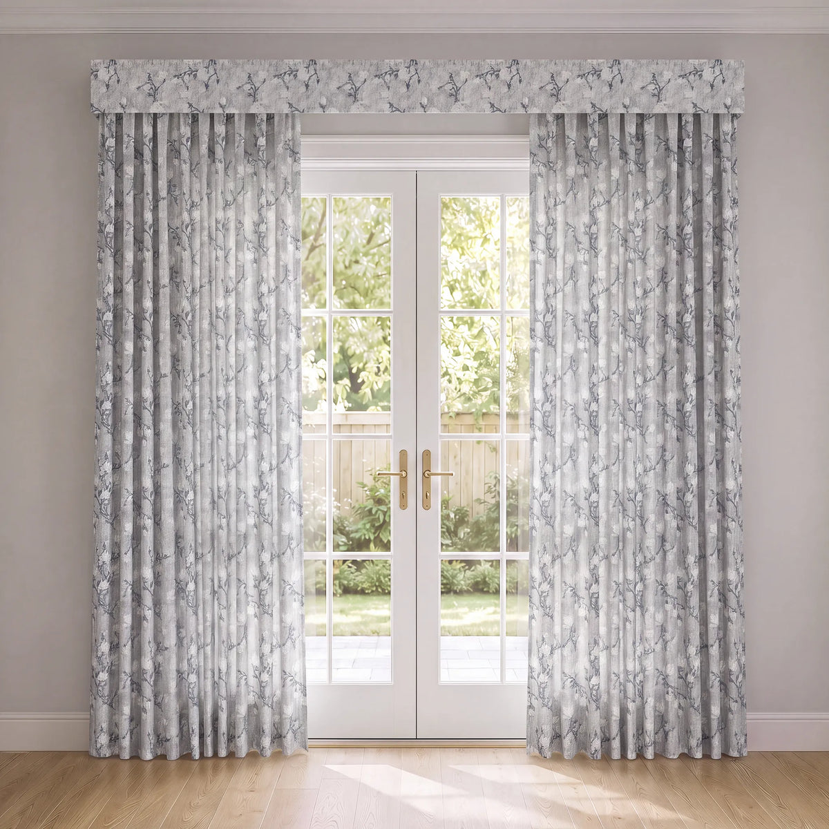 A pair of floor-length curtain panels with a matching valance, featuring a delicate gray floral pattern on a white background, styled in front of white French doors.