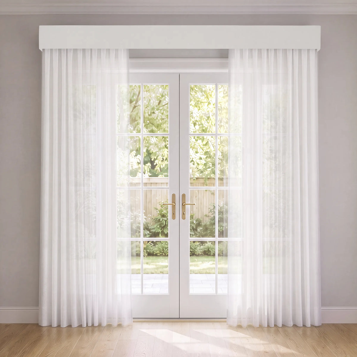 White sheer curtain panels with a matching white valance hanging on a pair of white French doors in a bright room with light wood floors.