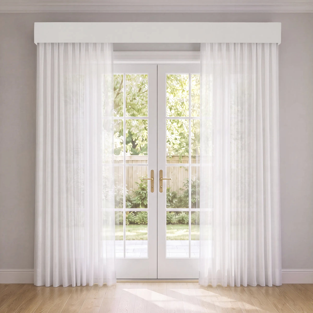 White sheer curtain panels with a matching white valance hanging in front of white French doors, set in a bright room with light wood floors and a garden view.
