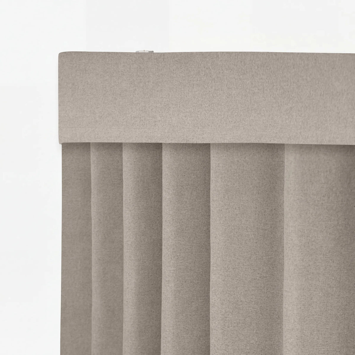 Close-up of a light taupe fabric curtain panel with vertical pleats and a wide top header, shown against a plain white background.