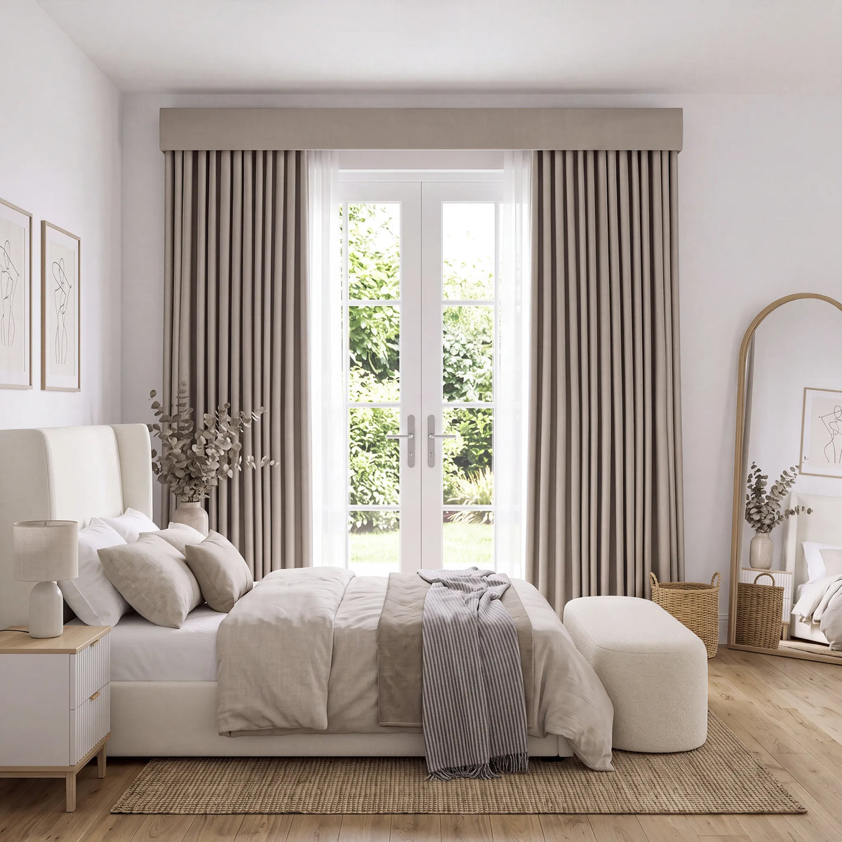 A styled bedroom interior featuring a pair of floor-length taupe curtains with a matching valance, hung on a large window behind a white bed with neutral bedding.