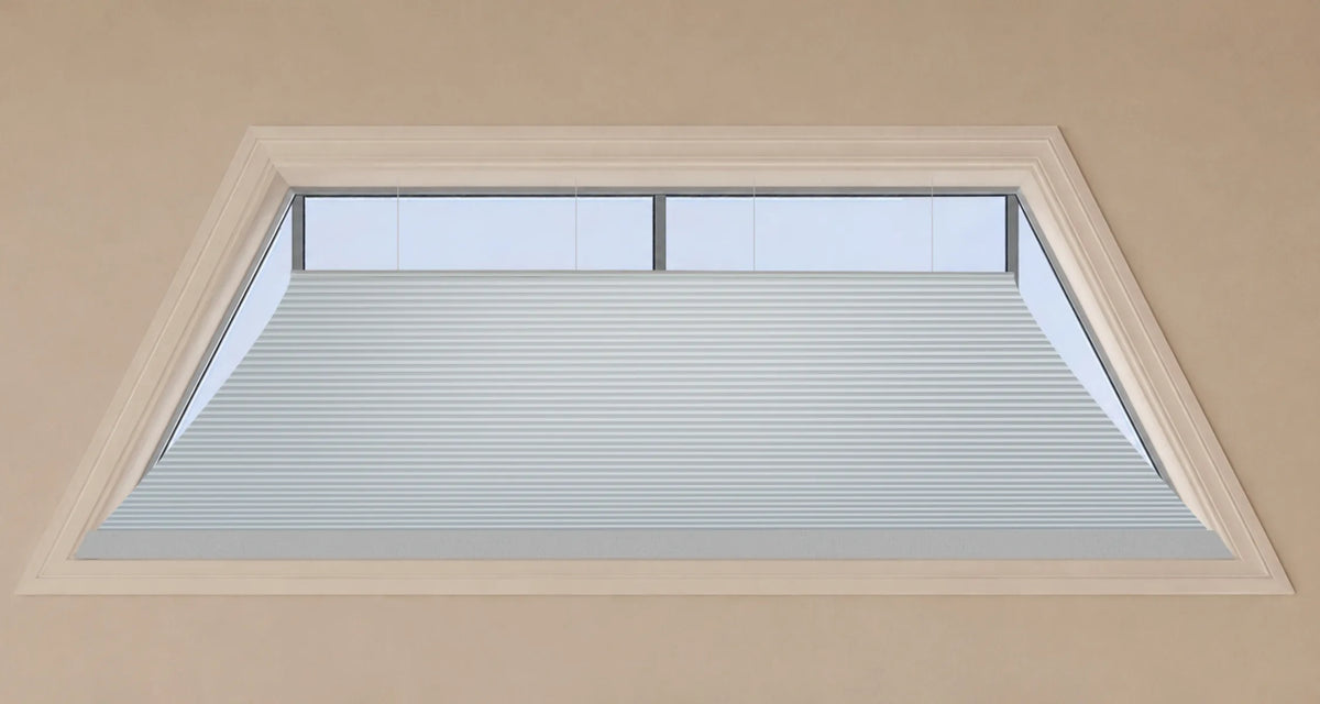 A close-up view of a light gray  Motorized Isosceles Trapezoid Cellular Shades installed inside a beige wall frame.
