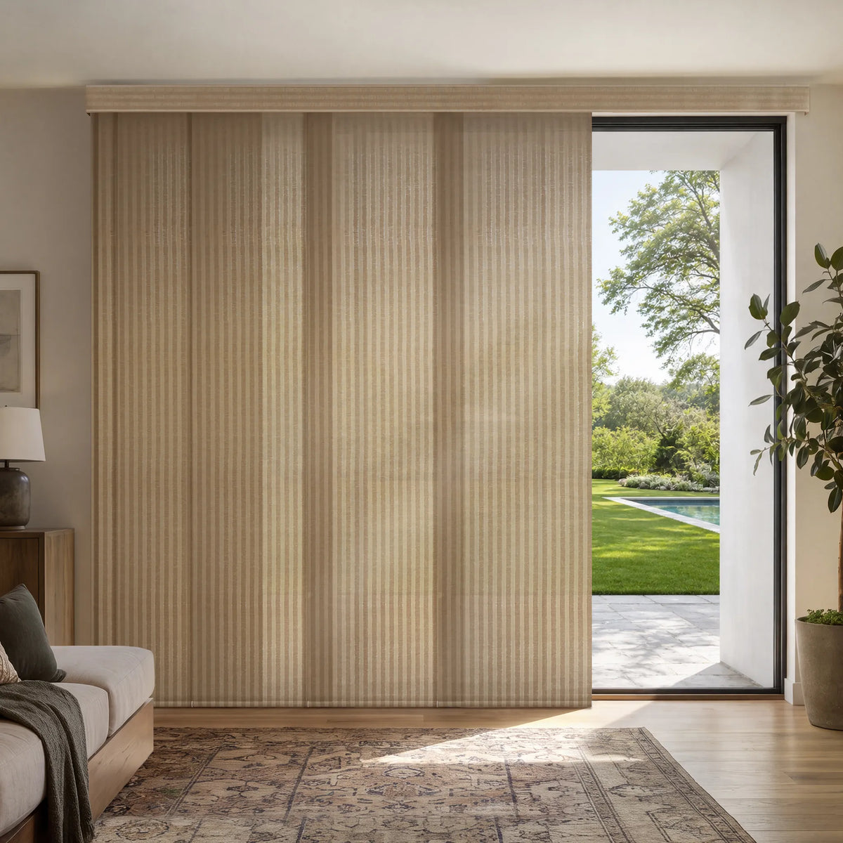 Beige Motorized Light Filtering Panel Track Blinds installed in a modern living room, with an open panel revealing a backyard pool and garden view.