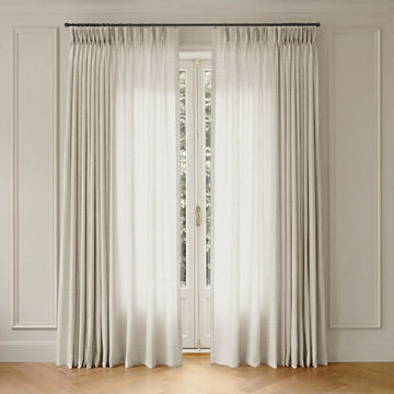 White curtains with rod hanging in front of a window with a neutral wall background