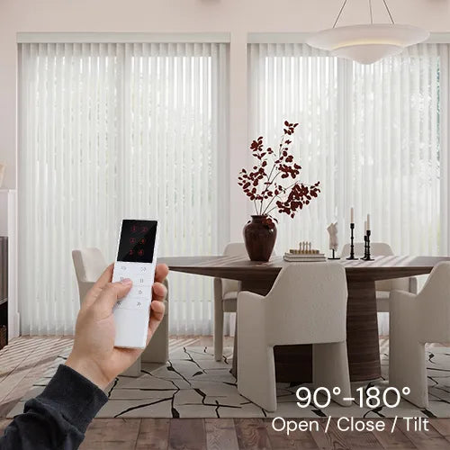 A hand holds a white remote control in a modern dining room setting with sheer vertical blinds on large windows, with a text overlay at the bottom right reading '90°-180° Open / Close / Tilt'.