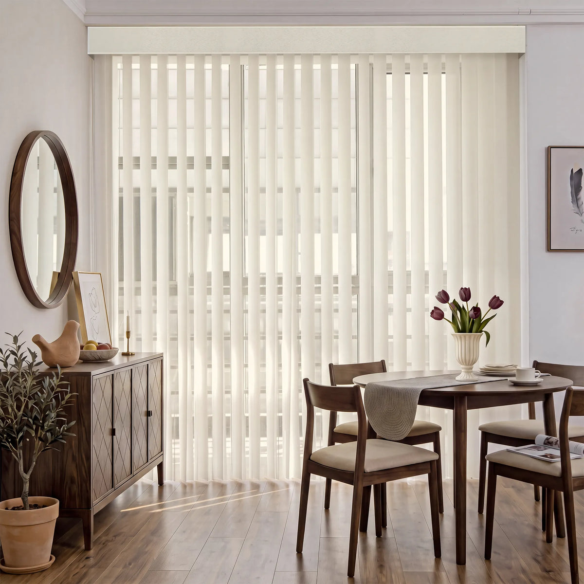 A dining room interior with tall cream Smart Sheer Vertical Blinds covering a large window or patio door, shown in a styled home setting with a wooden sideboard, dining table, chairs, wall art, and a potted plant.