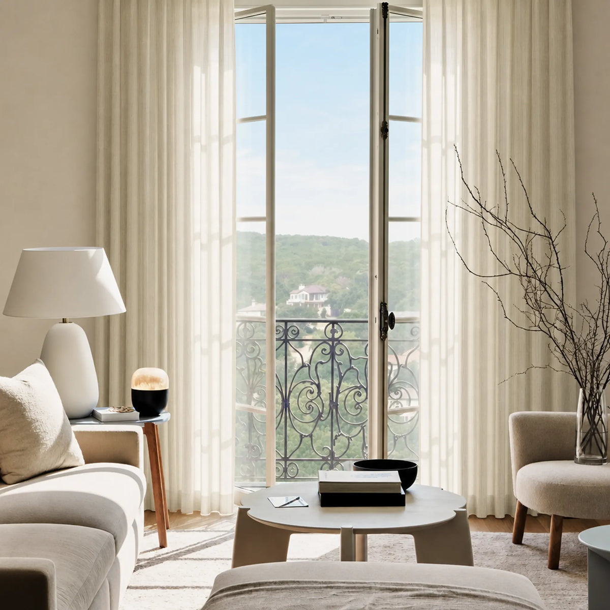 Modern living room with large windows, neutral decor, and a view of greenery outside.