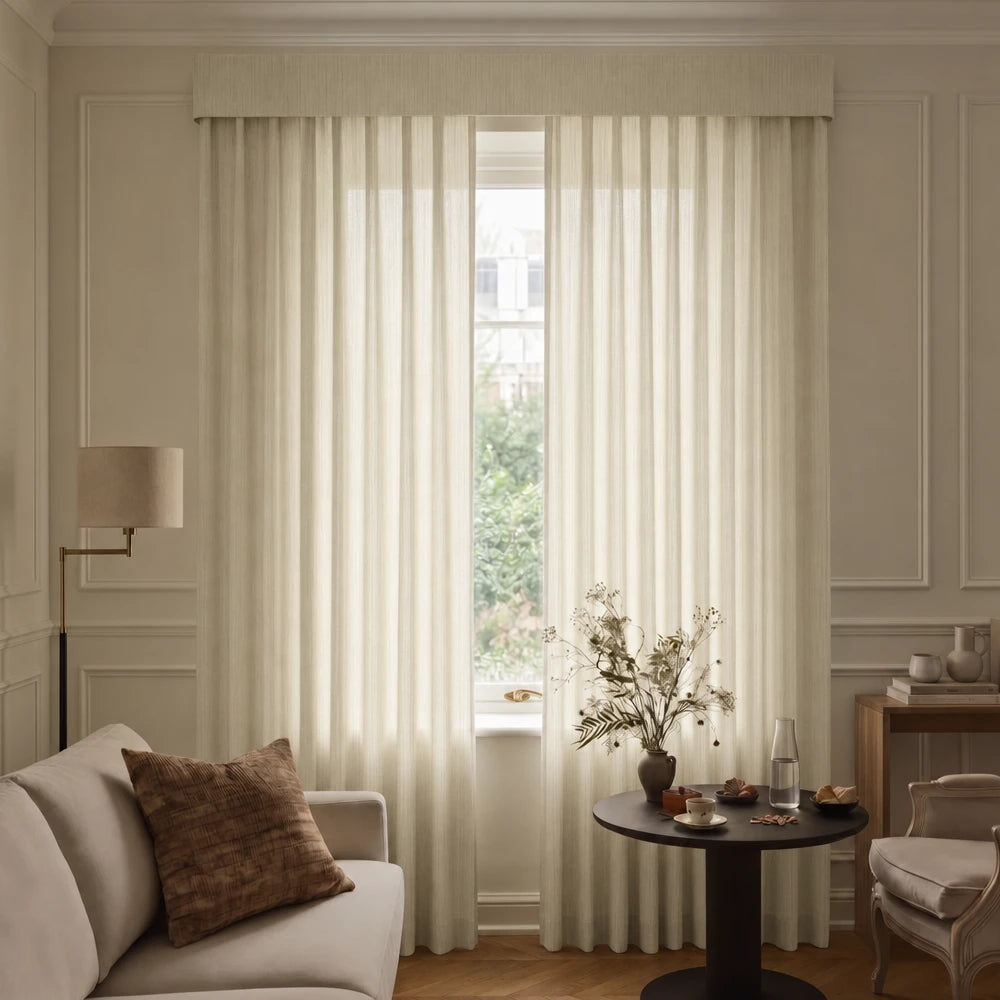Living room with beige curtains, a sofa, and a small table with decor items.