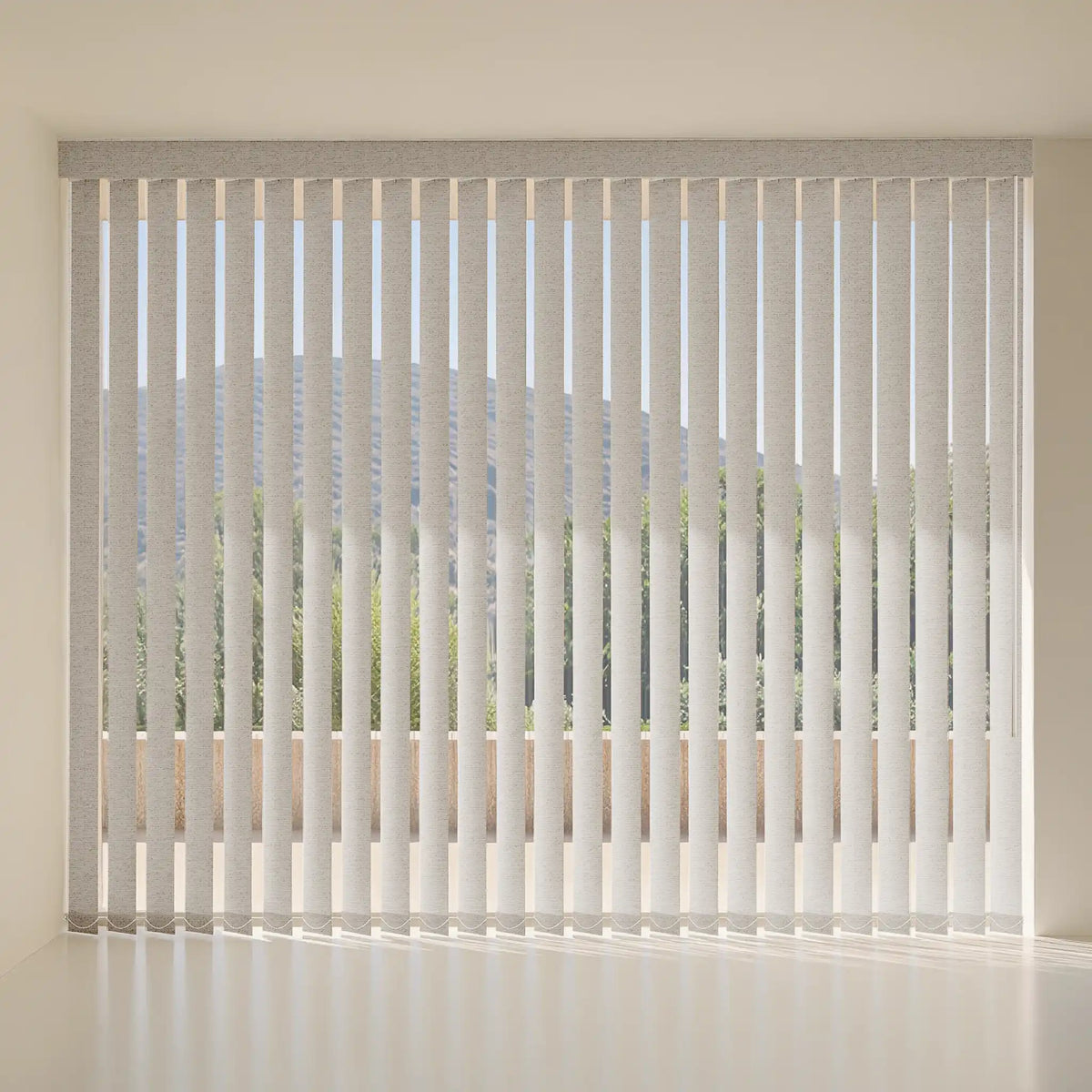 Vertical blinds in a light gray fabric, shown installed on a window in a bright, modern room with a white floor and wall.