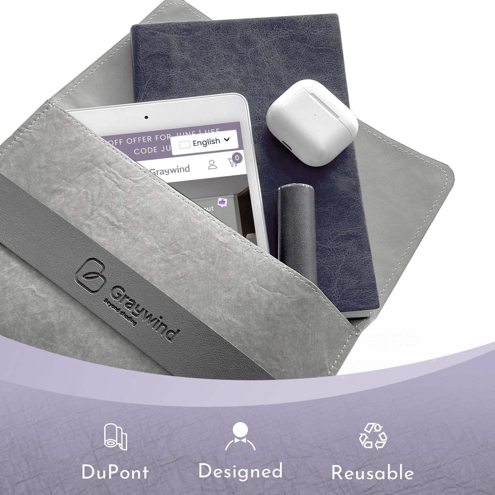 Gray DuPont reusable sleeve with tablet, notebooks, and wireless earbuds on white background