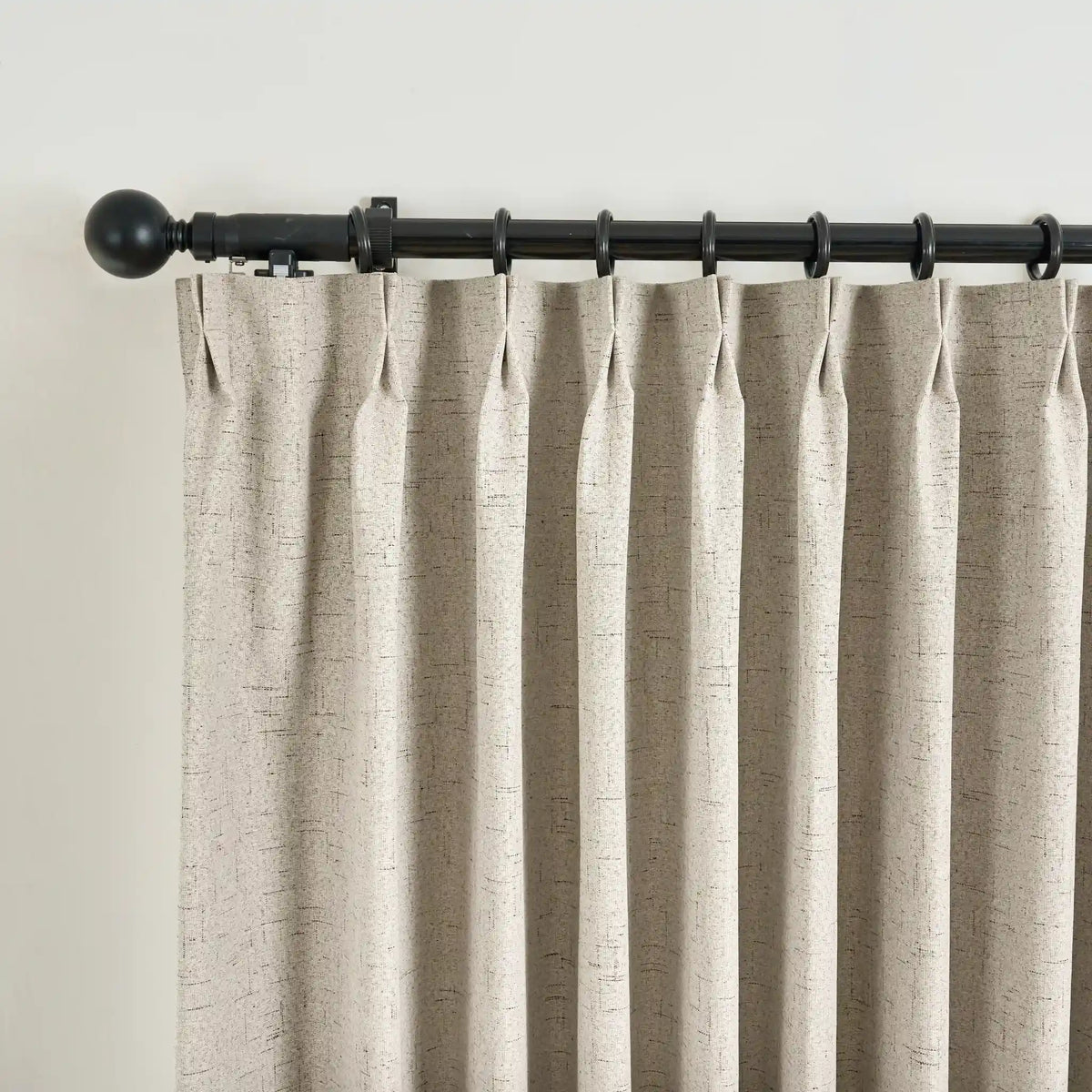 Beige curtain with a black rod on a plain background