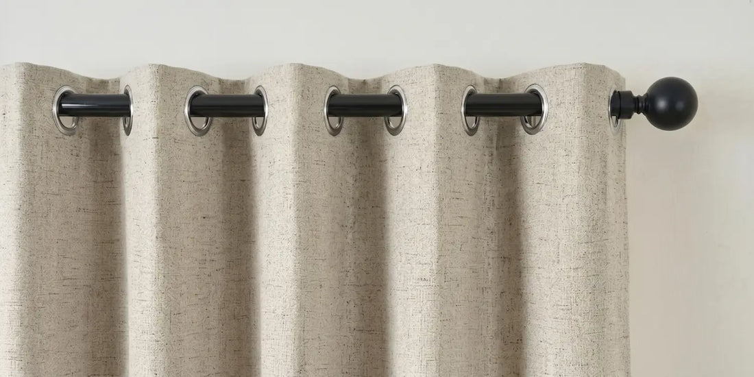 Beige curtain with black grommets on a plain background