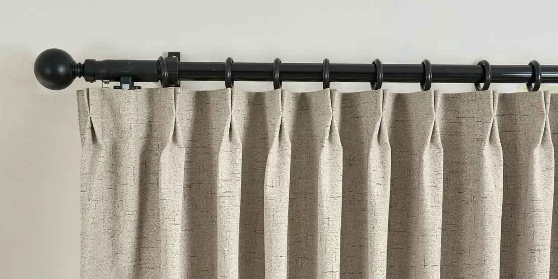 Beige curtain with a black curtain rod on a neutral background