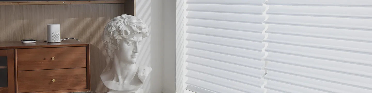 White window blinds partially covering a wooden cabinet with a decorative bust.