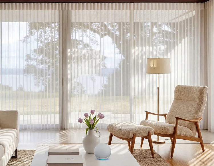 Modern living room with a beige armchair, ottoman, coffee table and sheer vertical window blinds.