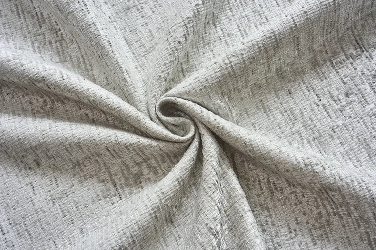 A close-up of light beige textured fabric gathered in a spiral, showing a woven linen-like pattern.