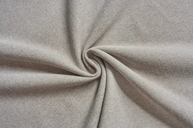 A close-up of light taupe-beige textured fabric gathered in a spiral swirl, showing its soft drape and fine woven texture.