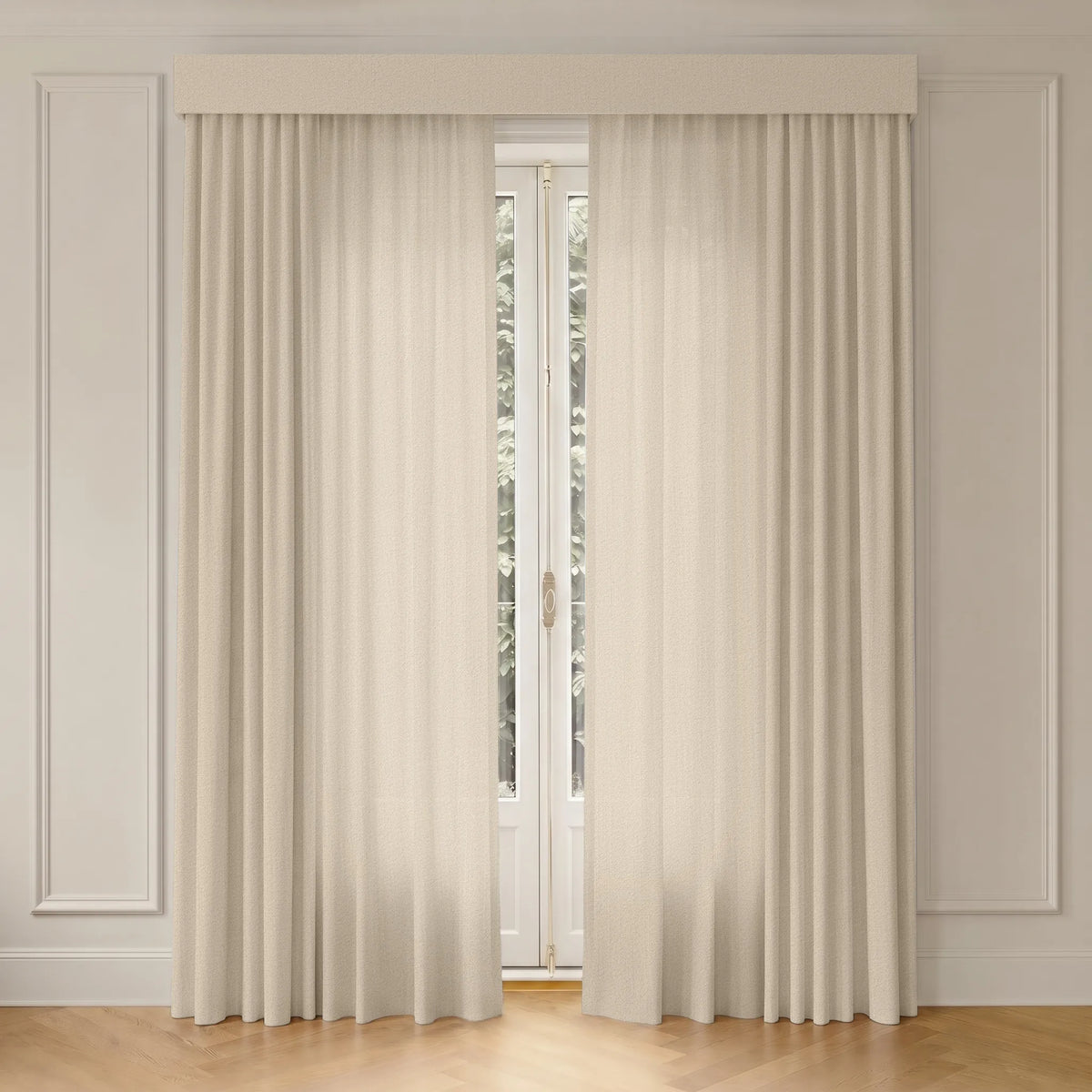 A pair of floor-length cream curtains with a matching valance hanging in front of a tall window in a classic room with white paneled walls and light wood flooring.