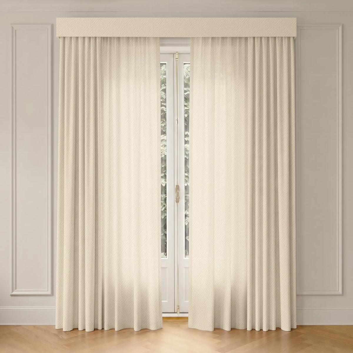 A pair of floor-length cream curtains with a matching pleated valance hanging in front of a tall window in a room with white paneled walls and light wood flooring.