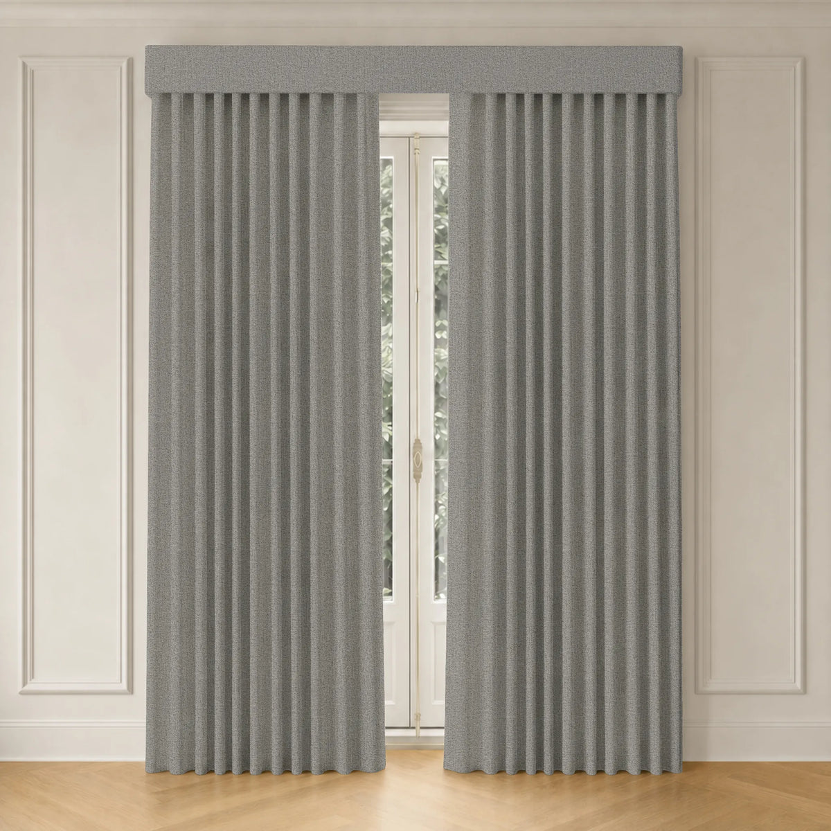 A pair of light gray pleated curtains hanging on a window in a room with cream paneled walls and light wood flooring.