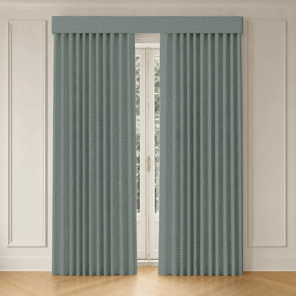 A pair of floor-length pleated curtains in a dusty sage green color, hanging on a window with a matching pleated valance in a room with cream paneled walls and light wood flooring.